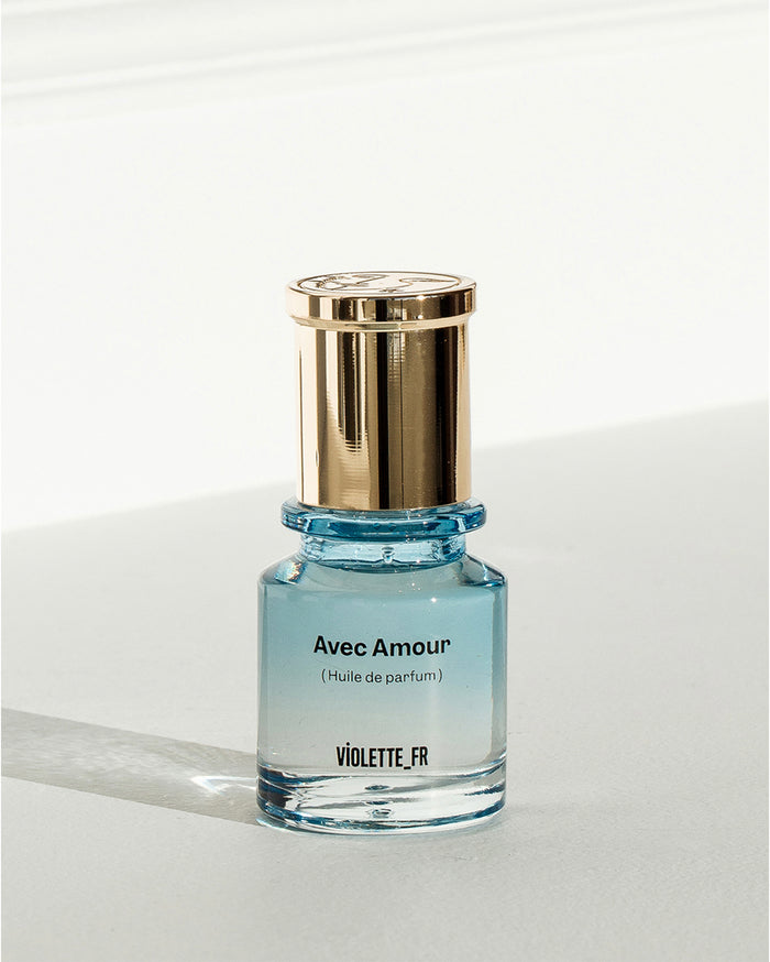 Avec Amour (Huile de parfum) VIOLETTE_FR on a small clear glass bottle with light blue liquid and a gold cap.