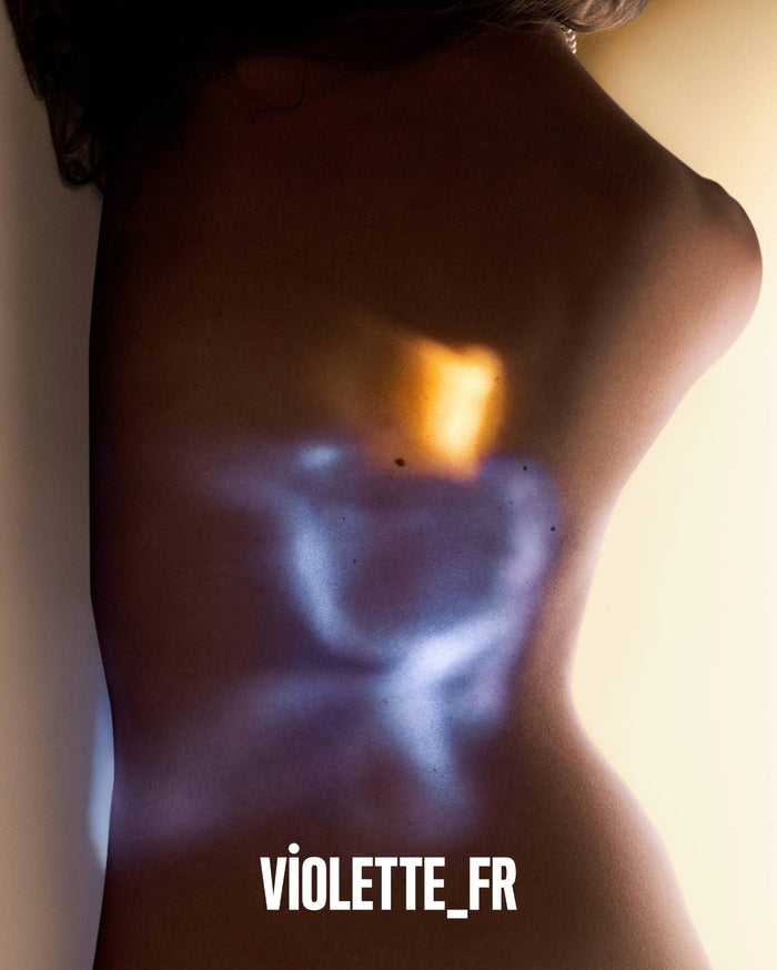 VIOLETTE_FR. A person's back and side torso with medium skin tone, illuminated by abstract light shapes: a bright orange-yellow rectangle on the upper back and a light blue-purple abstract shape below it.