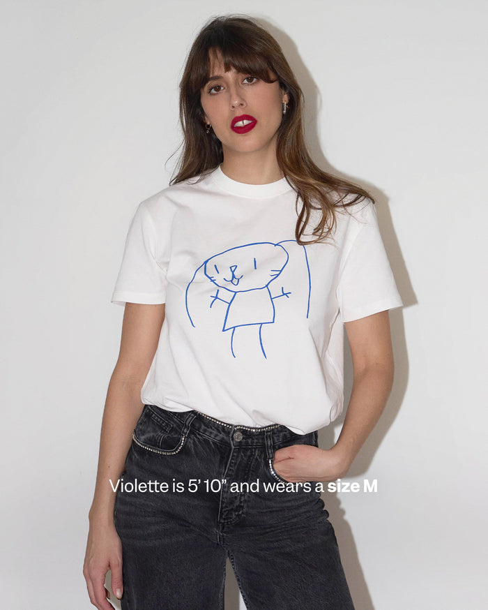 A medium skin tone woman wearing a white t-shirt with a blue bunny drawing and dark grey jeans. Violette is 5'10" and wears a size M.