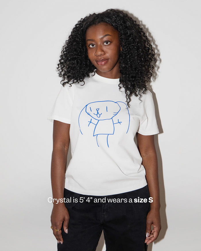 Crystal is 5' 4" and wears a size S. A woman with deep skin tone and curly dark hair wears a white t-shirt with a blue bunny drawing and black pants.