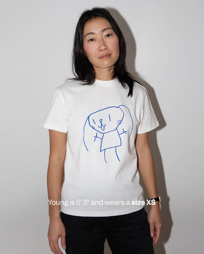 Young is 5' 3" and wears a size XS. A woman with medium skin tone wears a white t-shirt with a blue line drawing of a rabbit-like character.