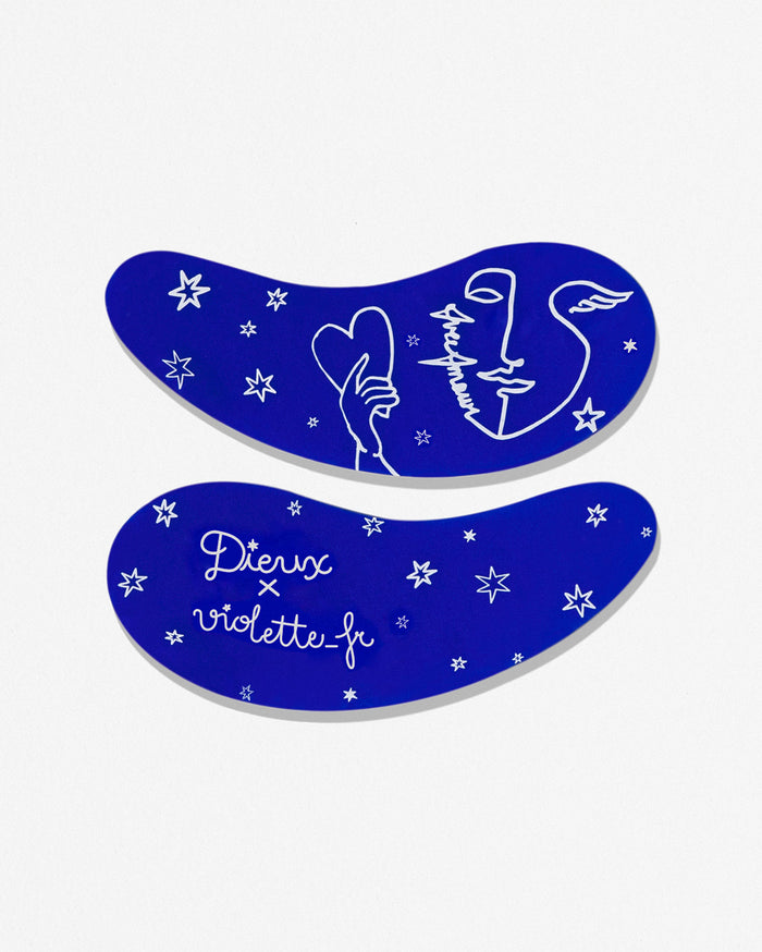 Two royal blue eye patches with white line art and stars. The top patch says "Fleur Amour" and shows a stylized face with wings and a hand holding a heart. The bottom patch says "Dieux x violette_fr".