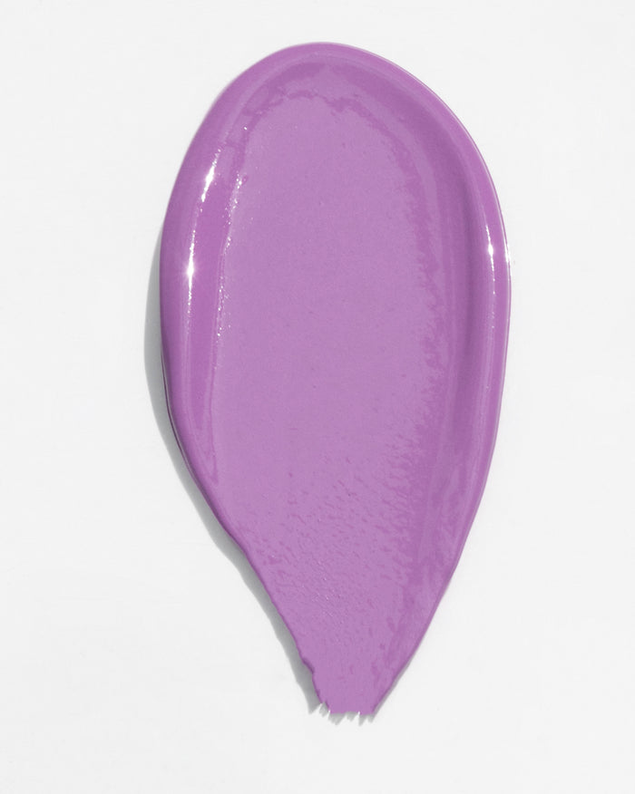 A single, elongated, petal-shaped swatch of a vibrant lavender-purple cream product with a glossy finish.