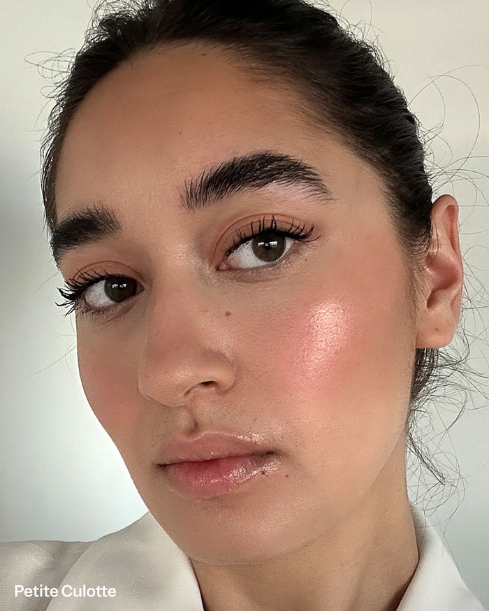 Petite Culotte. Close-up of a model with medium skin tone wearing a light pink blush and glossy pink lips.
